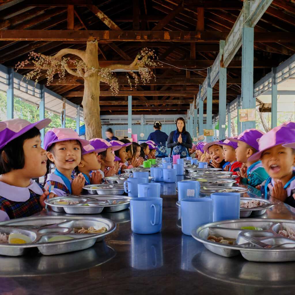 Betende Kinder in der Mensa einer Grundschule in Bangkok