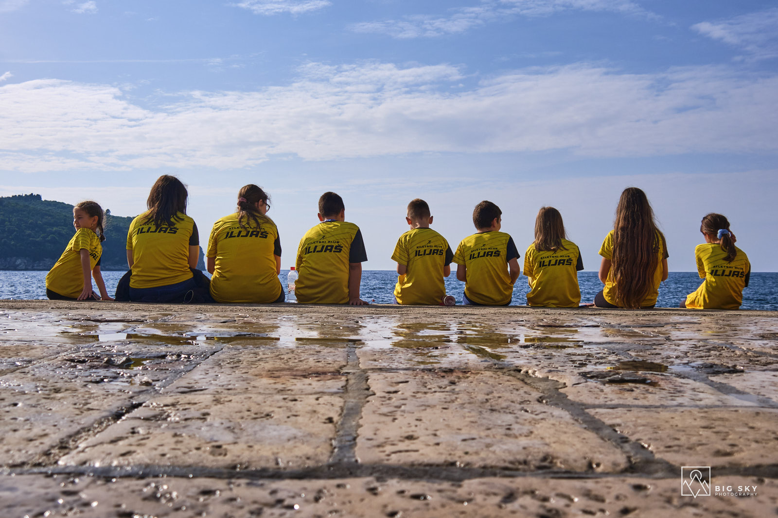 Kinder eines Sportvereins in gelben T-Shirts genießen den Blick auf das Meer vor Dubrovnik