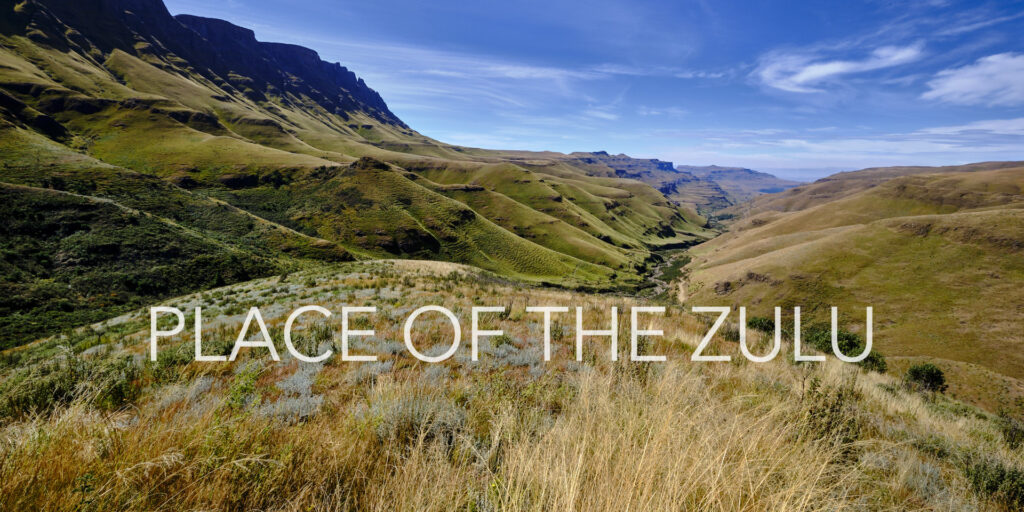 Blick von oben auf die grünen Hügel des Sanipasses unter blauem Himmel in Kwazulu-Natal