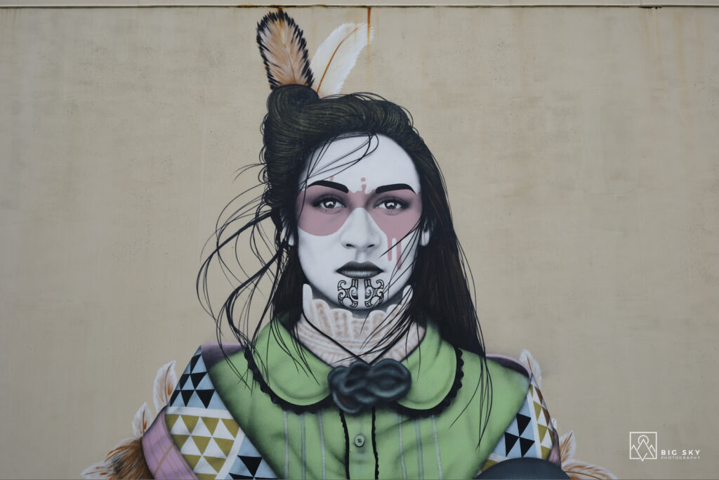Graffito „Taaniko“ des irischen Straßenkünstlers Fin DAC in Mount Maunganui. Es zeigt eine Maori-Frau mit traditionellen Moko-Kinn-Tattoos.